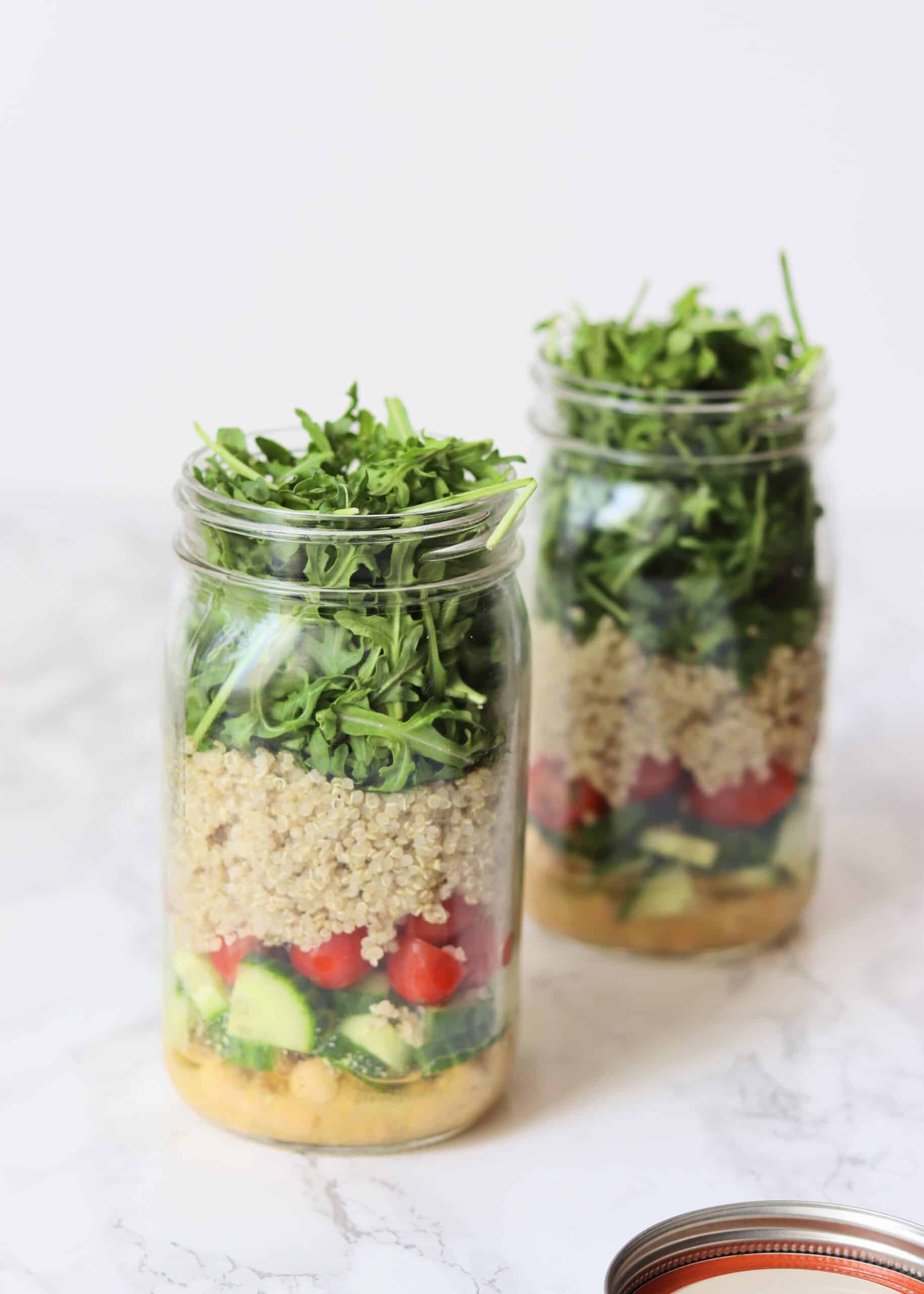 Two quinoa mason jar salads with layered ingredients
