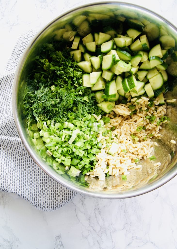 Orzo, chopped cucumber, dill, and scallions in a bowl