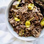 Chuck Roast cooks low and slow in the crockpot and results in a tangy, slightly spicy, shredded Italian Beef that your family will love. Perfect on its own or in hoagie buns for Italian Beef Sandwiches. Recipe at KathleensCravings.com #slowcookerrecipes #chuckroastrecipes #slowcookerbeef #italianbeefrecipe