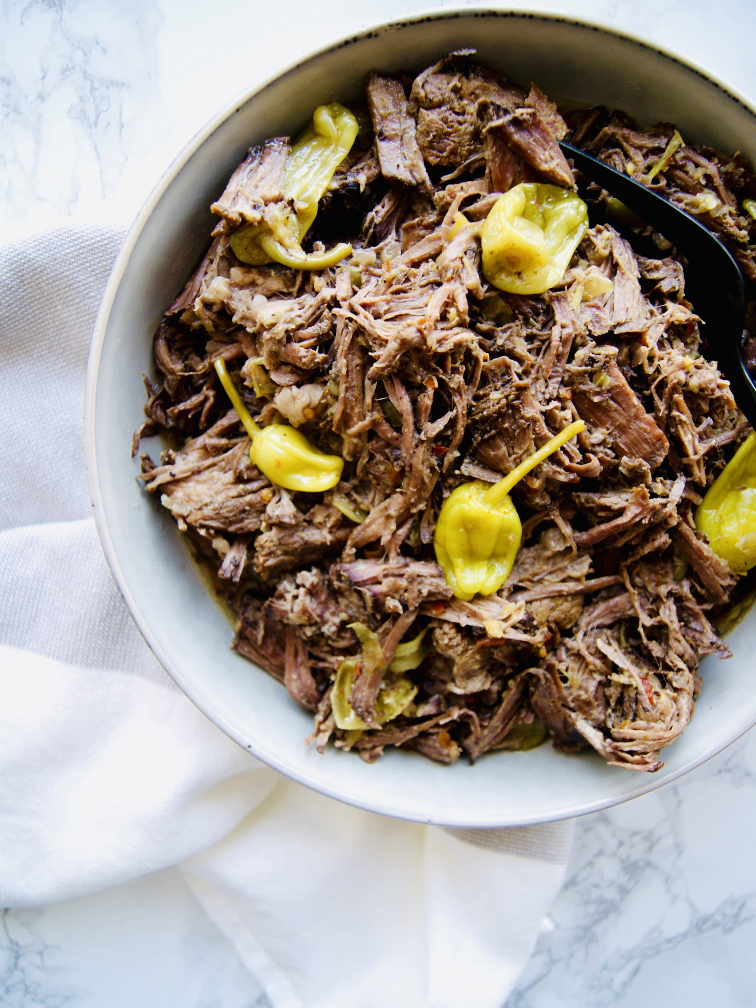 Chuck Roast cooks low and slow in the crockpot and results in a tangy, slightly spicy, shredded Italian Beef that your family will love. Perfect on its own or in hoagie buns for Italian Beef Sandwiches. Recipe at KathleensCravings.com #slowcookerrecipes #chuckroastrecipes #slowcookerbeef #italianbeefrecipe