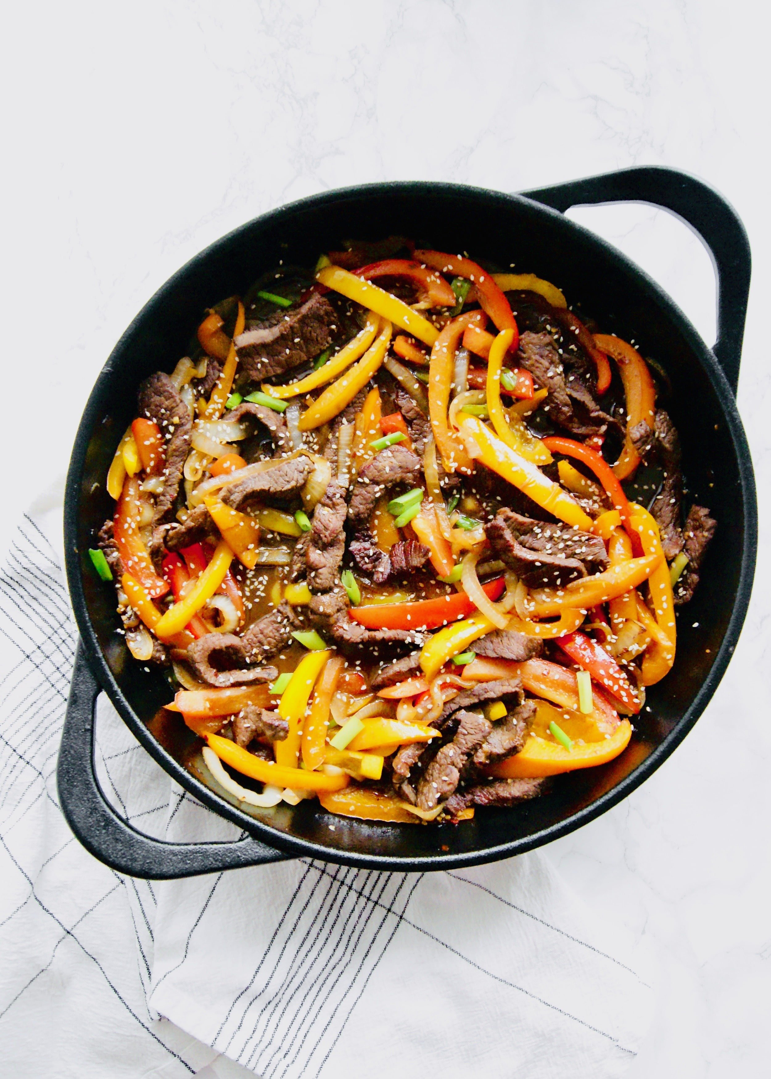 Beef, peppers, and onions in a cast iron skillet
