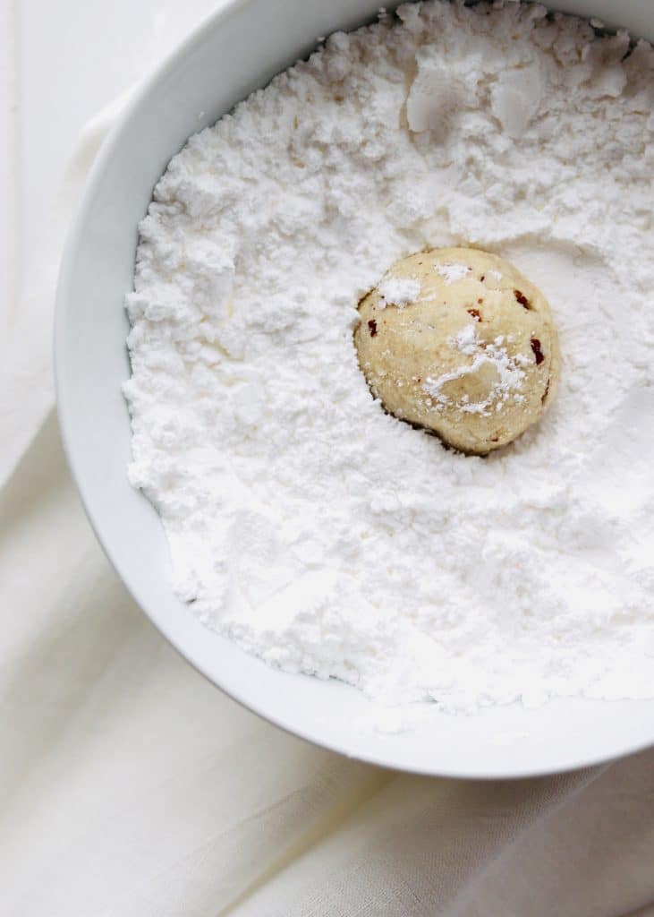 snowball cookies in bowl of powdered sugar