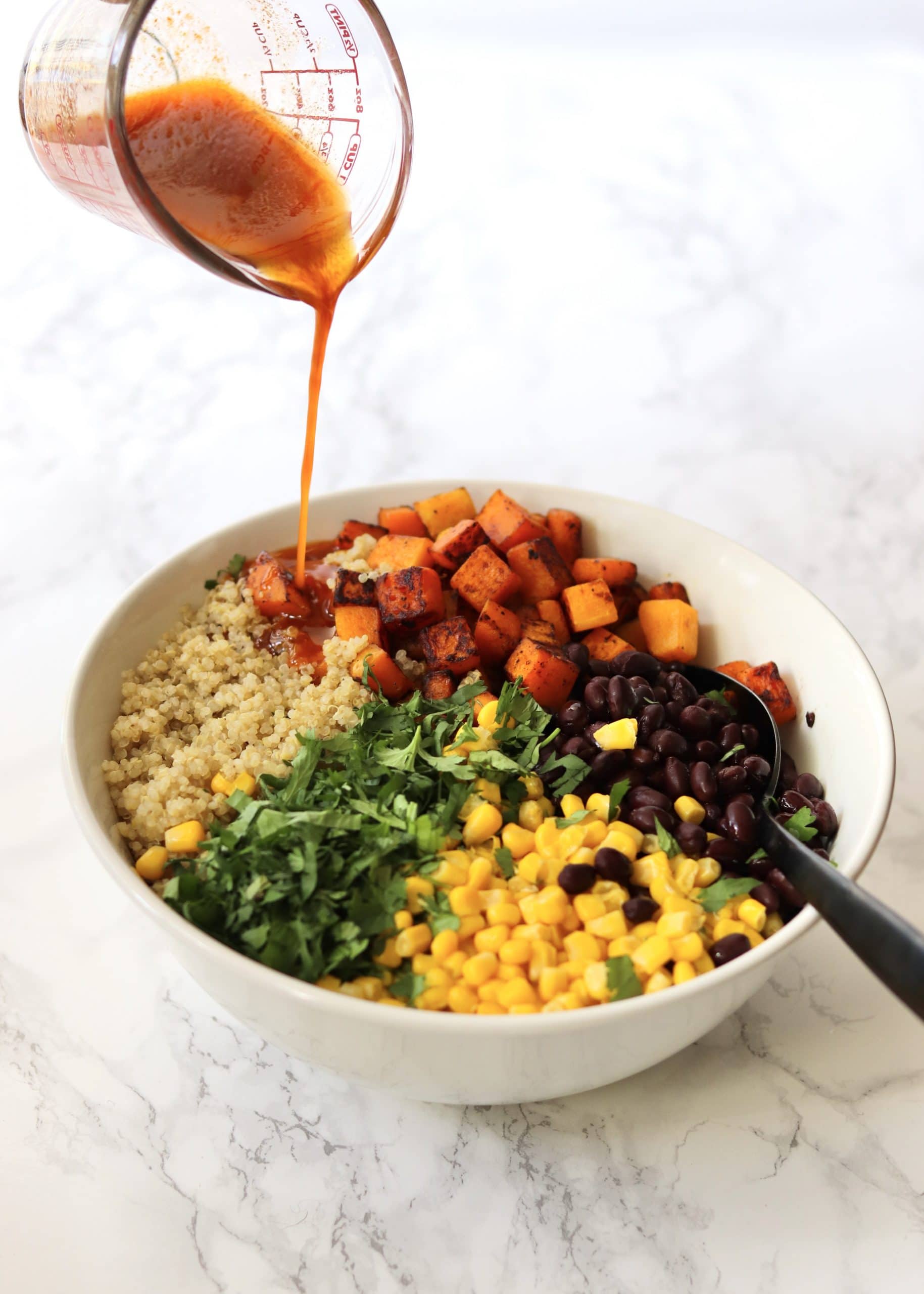 Dressing being poured into the quinoa salad