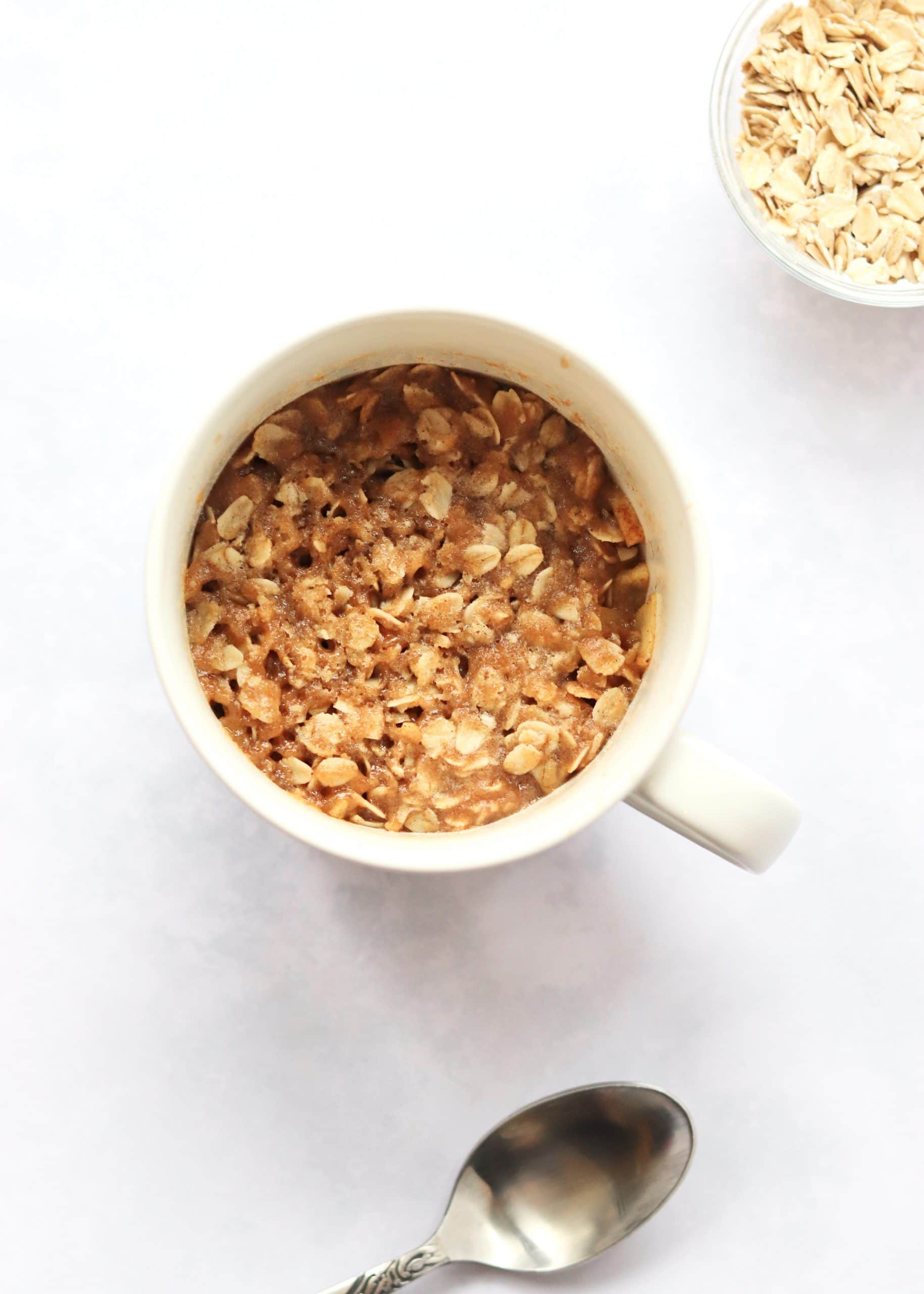 Mug Apple crisp with a spoon and small bowl of oats
