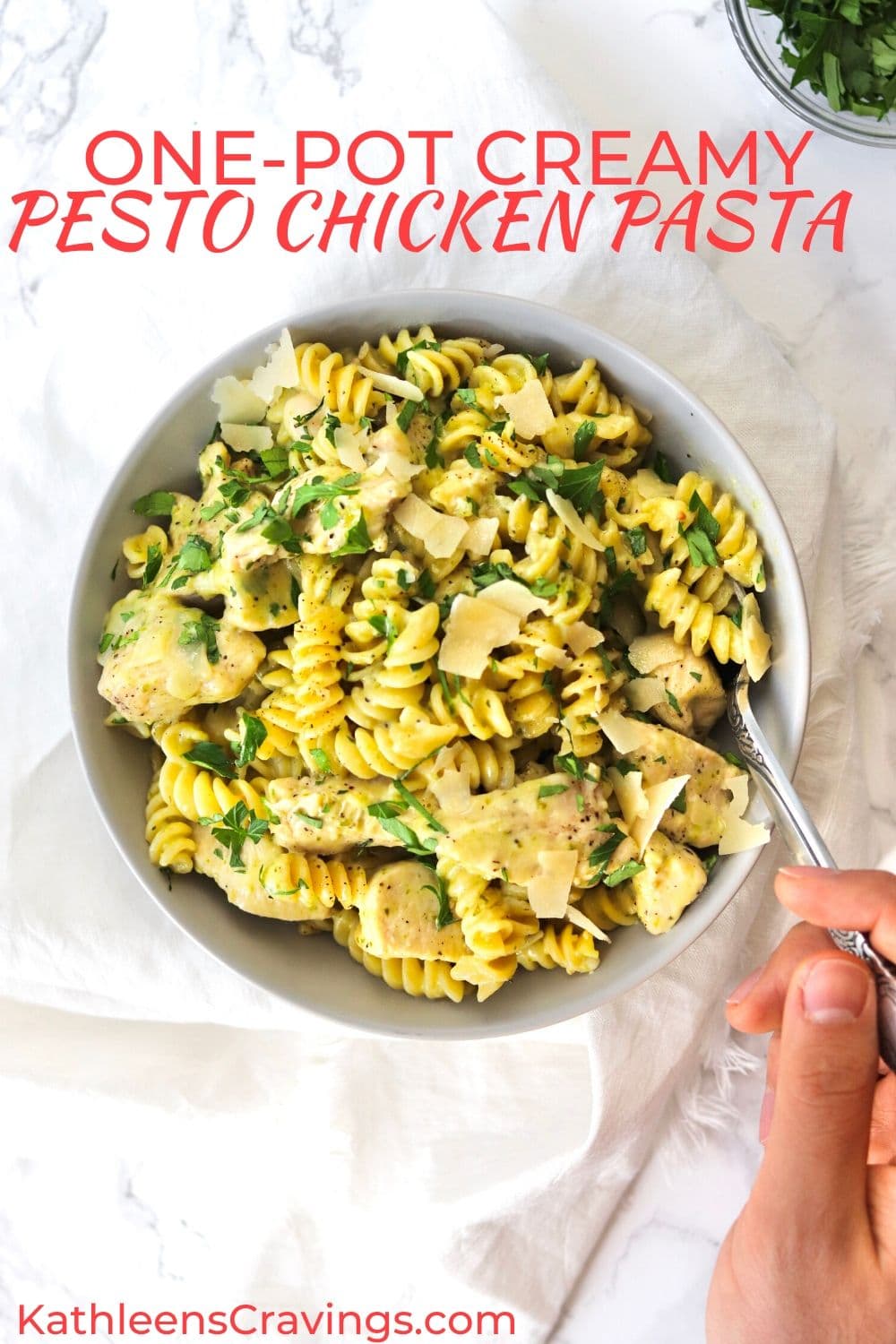 creamy pesto chicken pasta in a bowl with a fork and parsley