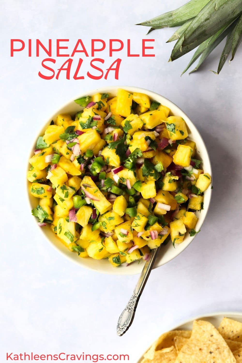 Pineapple salsa in bowl with spoon and pile of tortilla chips.