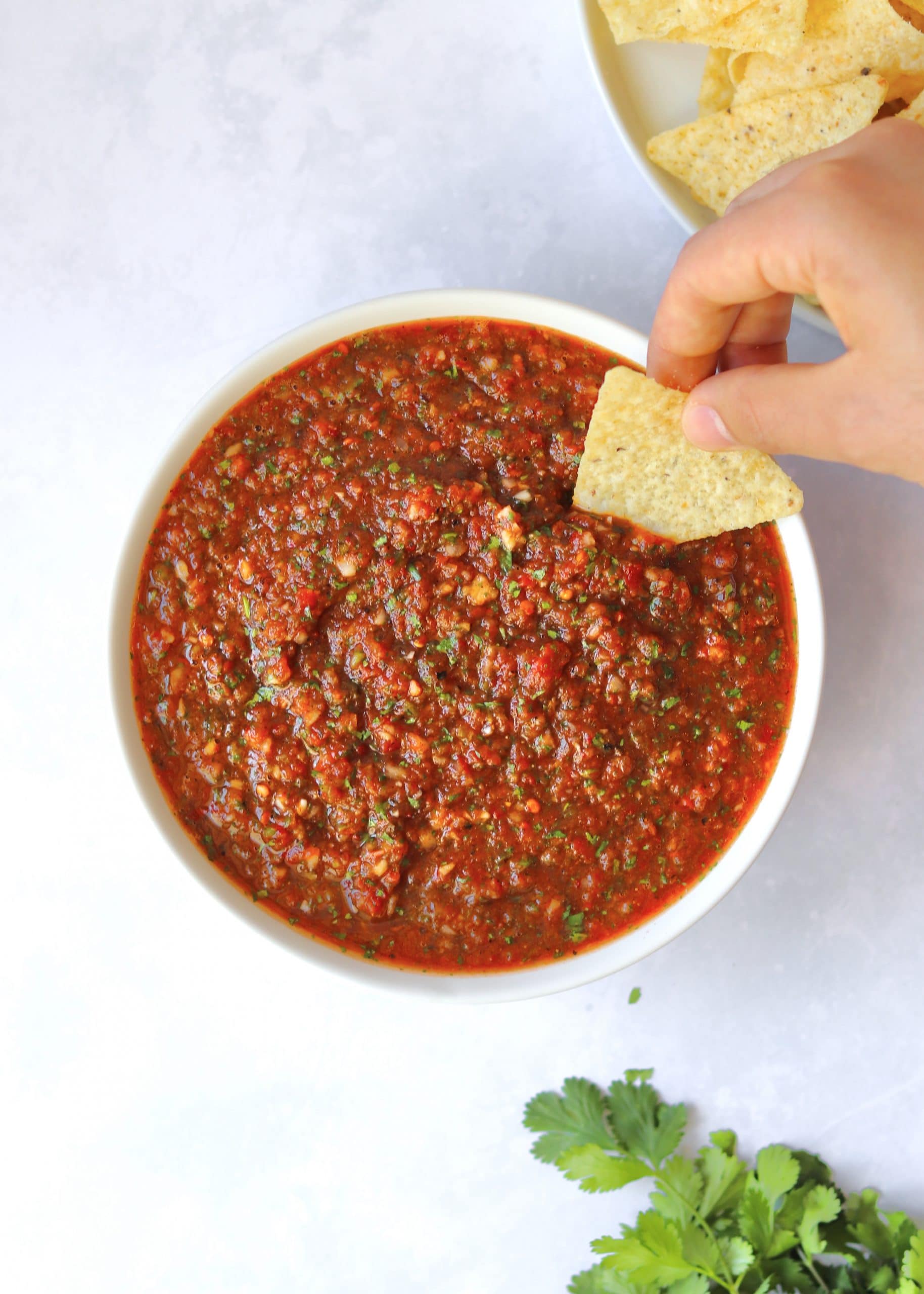 Hand dipping chip into bowl of salsa