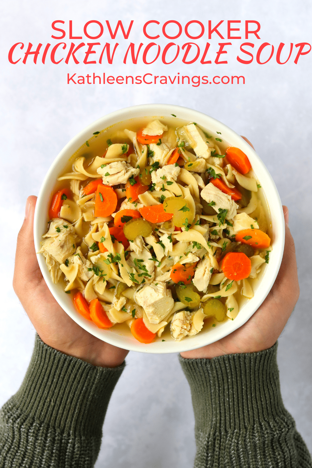 Hands holding bowl of chicken noodle soup made in the slow cooker.