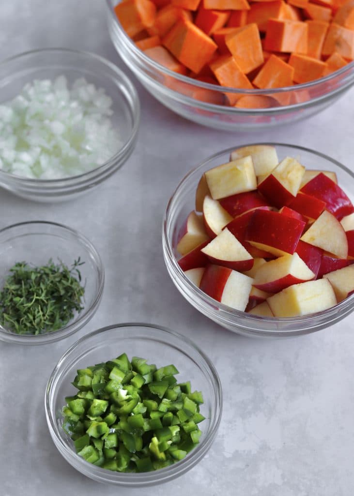 Ingredients in glass bowls - chopped sweet potato and apple, diced jalapeño, fresh thyme, and diced onion.