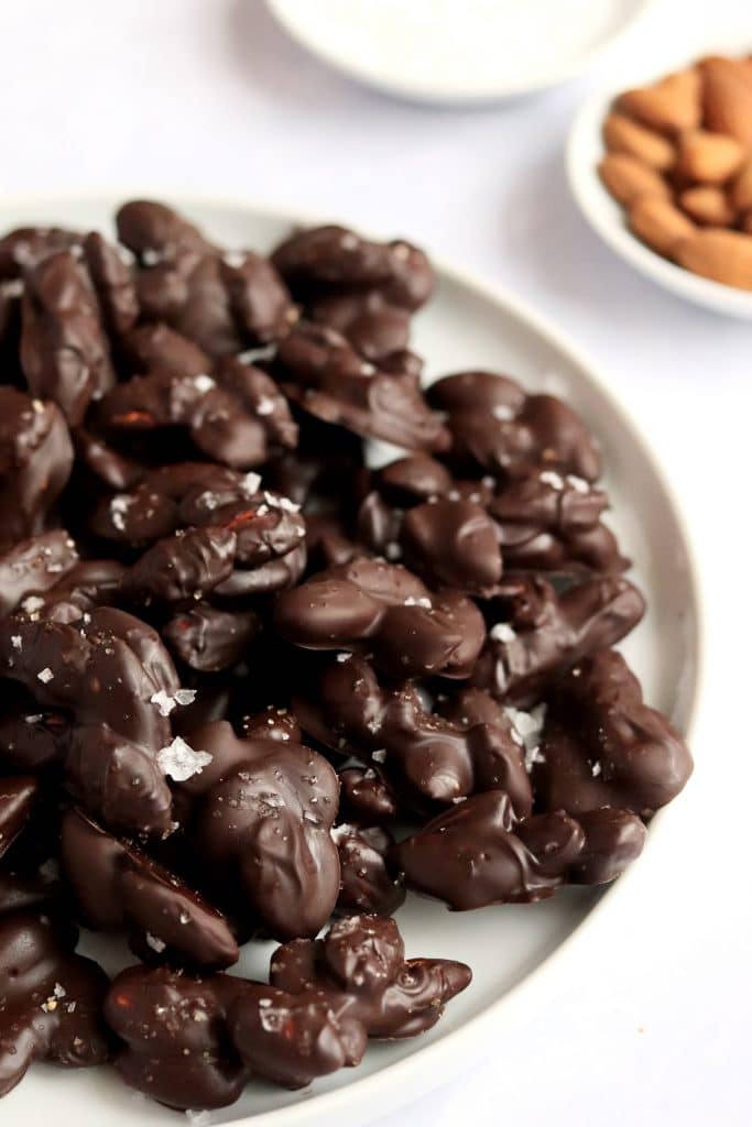 Plate of chocolate almond clusters topped with flaky sea salt
