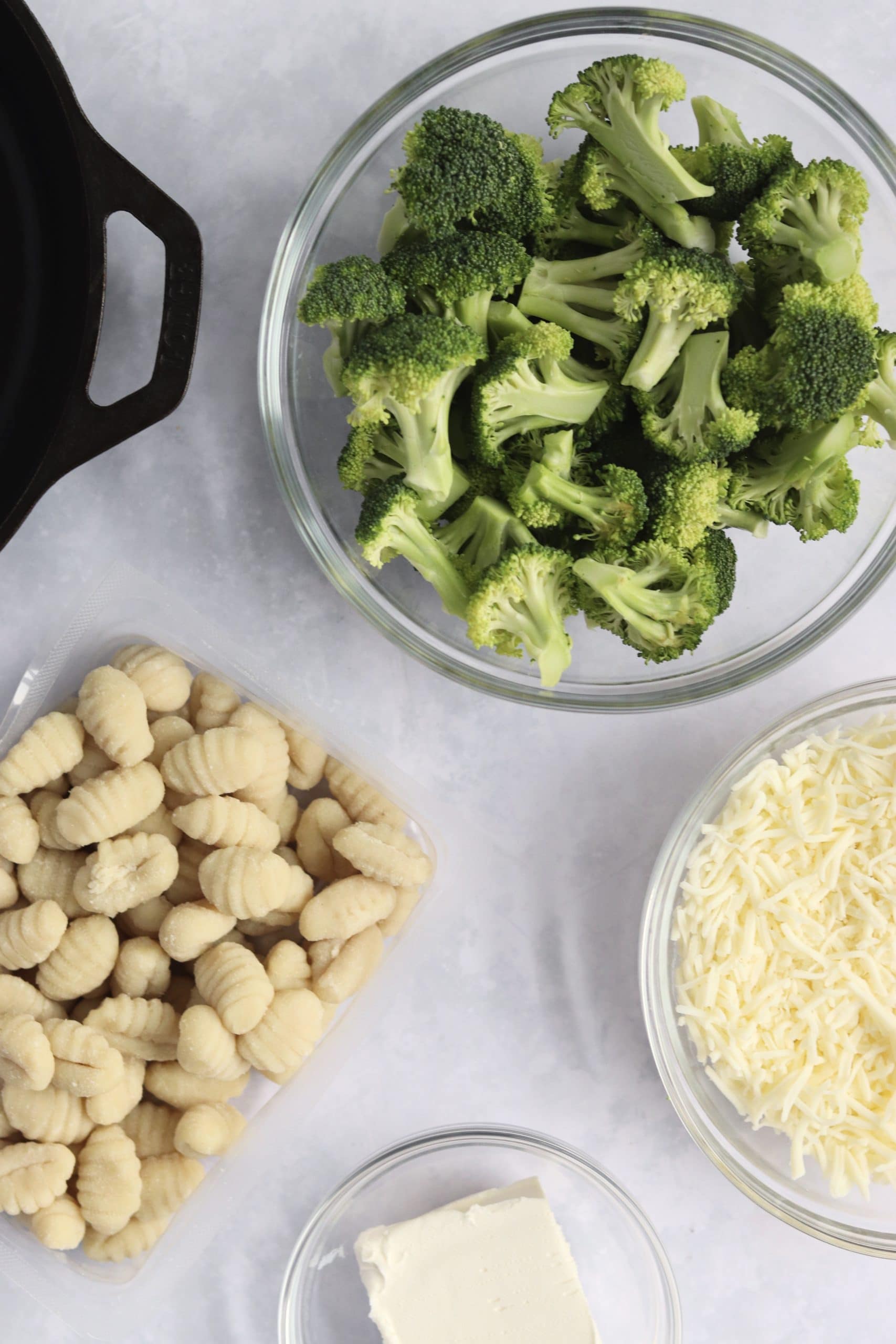 Recipe ingredients in bowls - broccoli florets, store-bought gnocchi, cream cheese, and shredded cheese