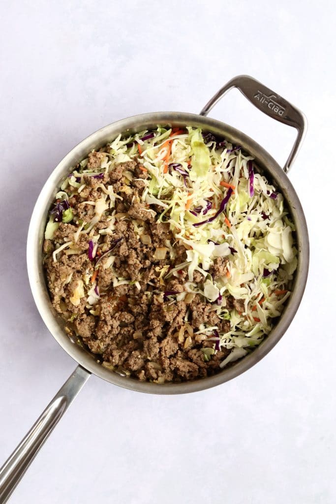 Ground pork and coleslaw mix in a skillet