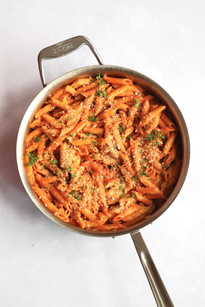 Vegan creamy tomato pasta topped with garlic breadcrumbs in a pan