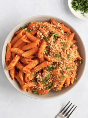 bowl of vegan creamy tomato pasta with bread crumbs