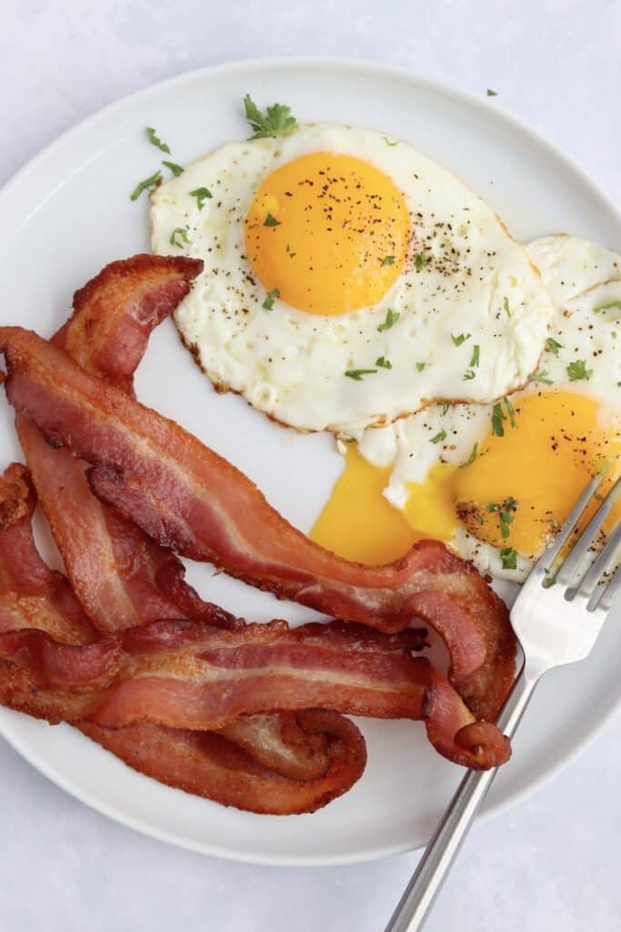 crispy air fryer bacon and sunny side eggs with a runny yolk on a plate