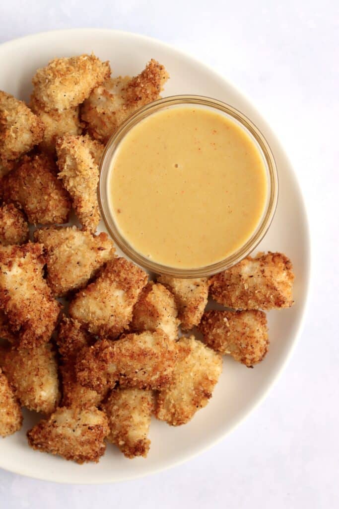 Air fryer chicken nuggets on a plate with a bowl of honey mustard