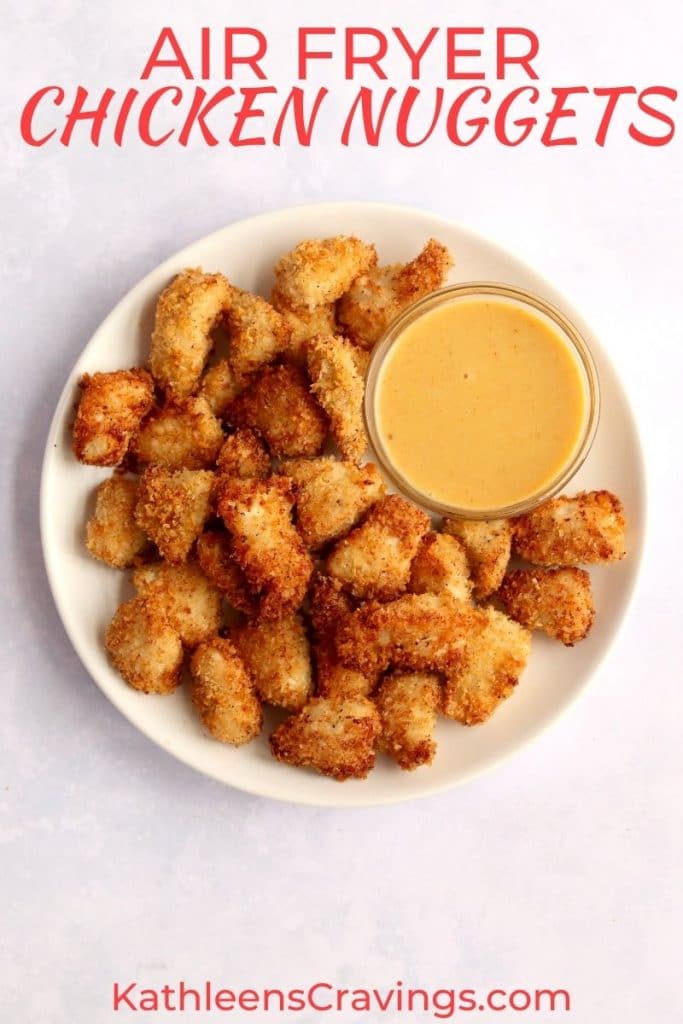 Air fryer chicken nuggets with a bowl of honey mustard sauce on a white plate