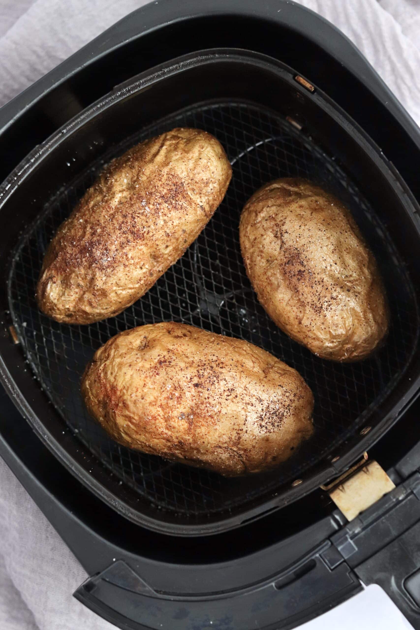 Three baked potatoes in an air fryer