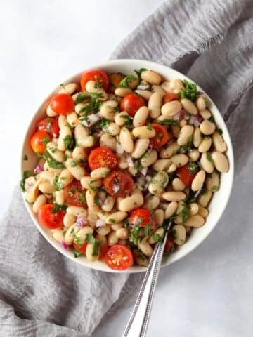 Bowl of white bean salad with tomatoes and fresh herbs