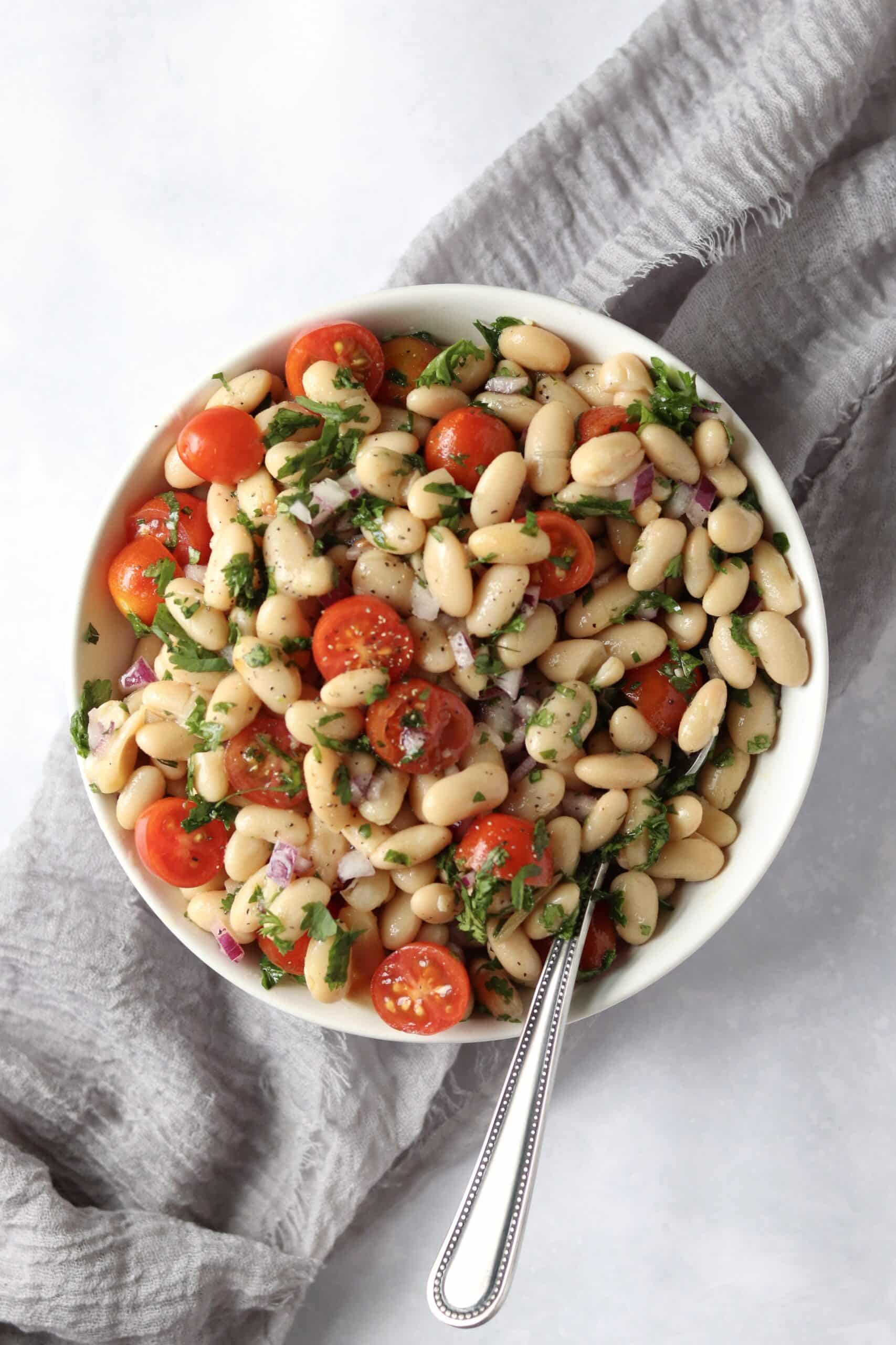 Bowl of white bean salad with tomatoes and fresh herbs