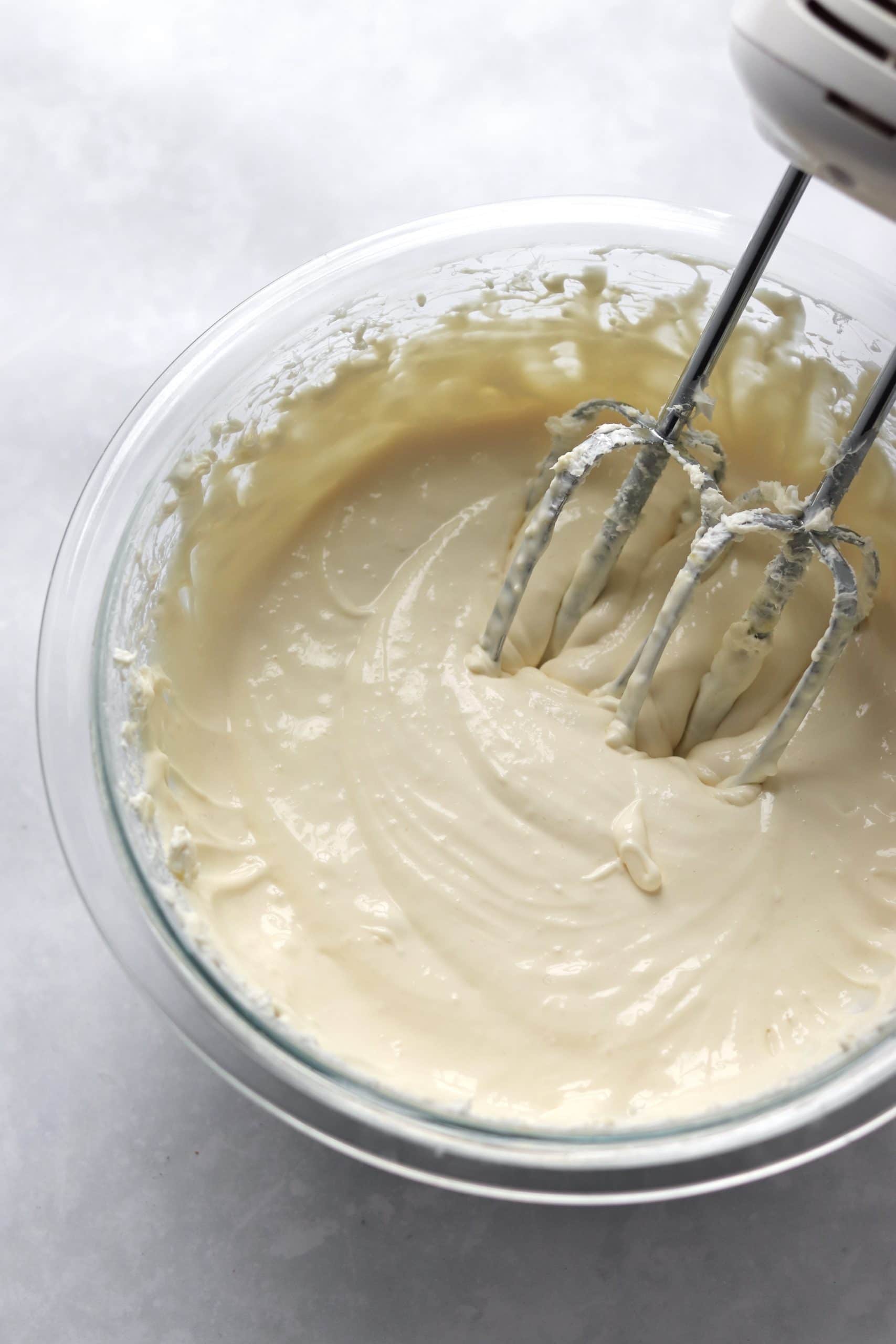 Cheesecake batter in a bowl with a hand mixer