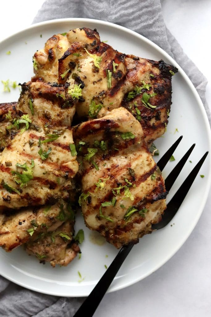 Grilled chicken thighs on a plate with a fork