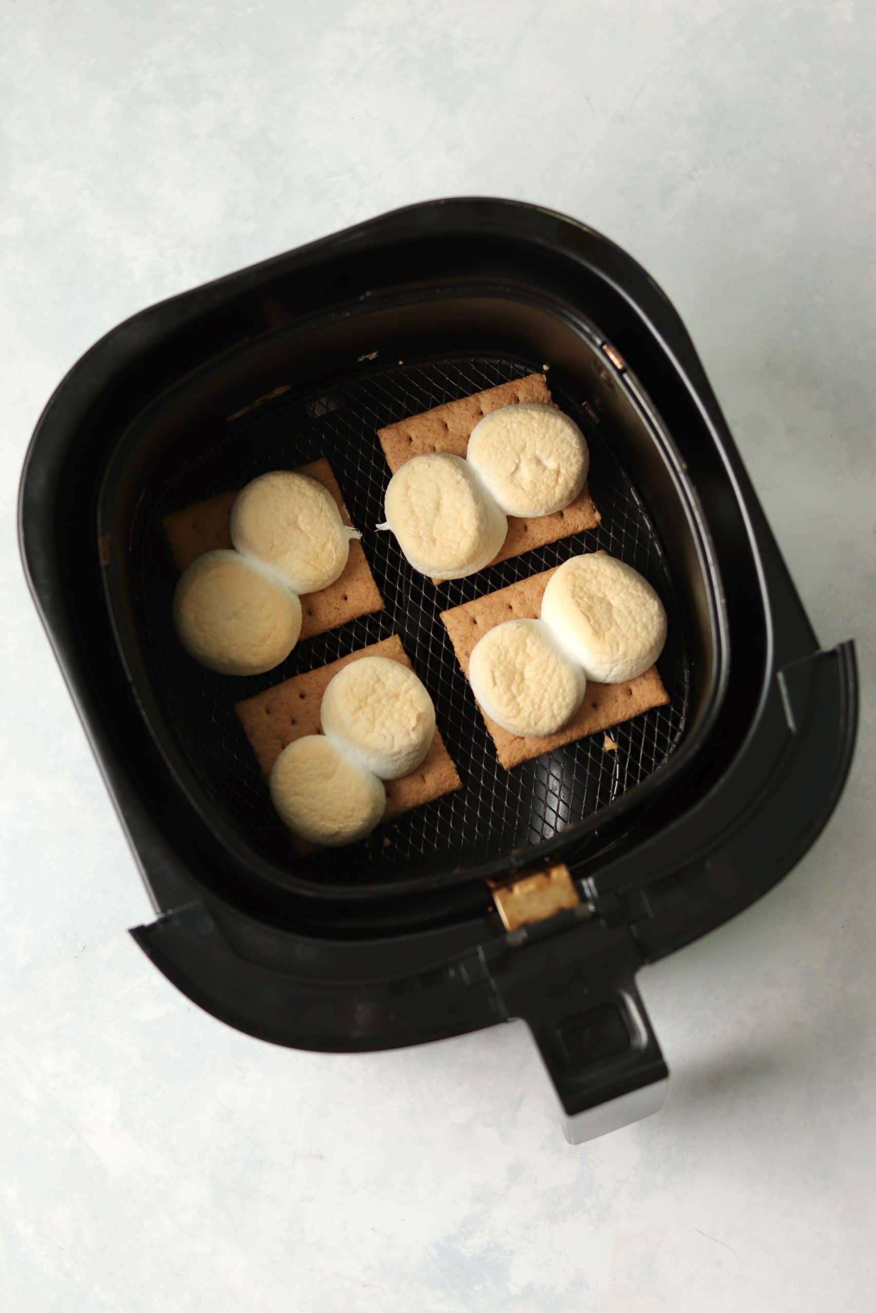 toasted marshmallows on graham crackers in air fryer basket.