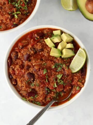 Bowls of vegetarian quinoa chili topped with avocado