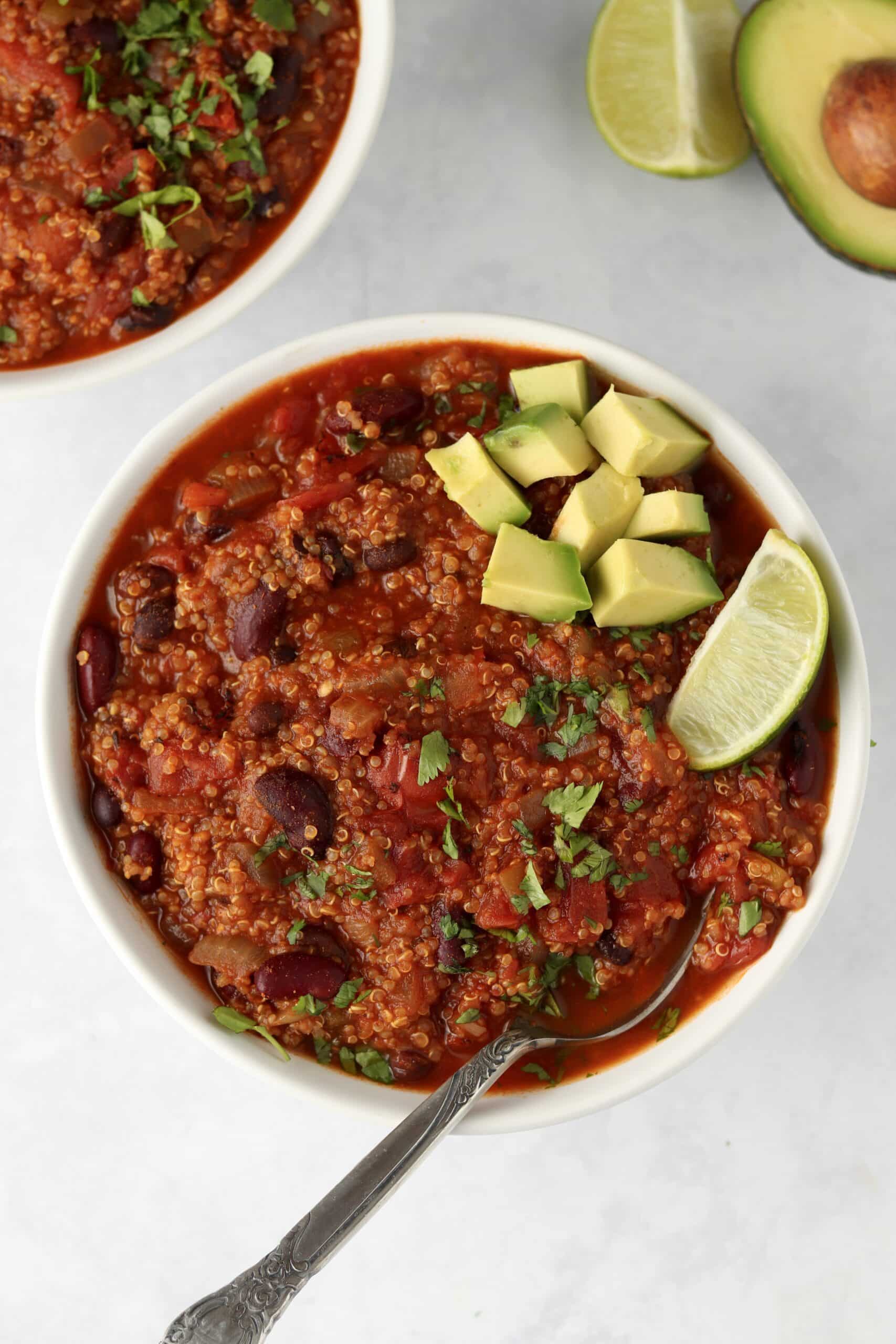 Bowls of vegetarian quinoa chili topped with avocado.