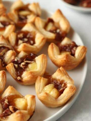 brie puff pastry bites on a plate with pecans