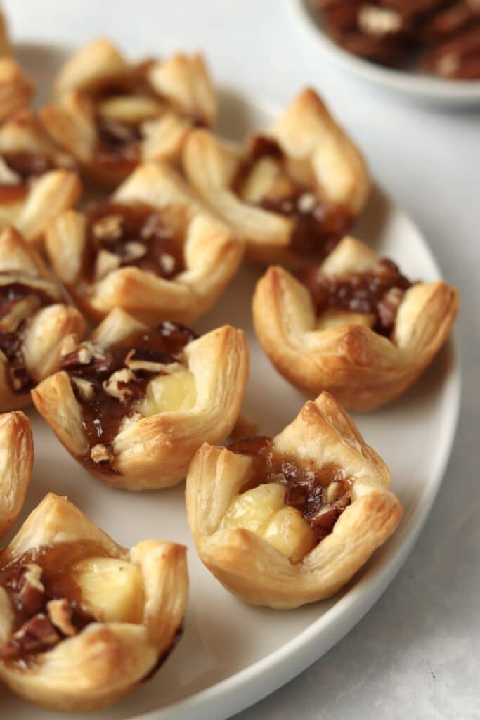 brie puff pastry bites on a plate with pecans