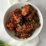 bowl of baked Korean wings with sesame seeds and green onions