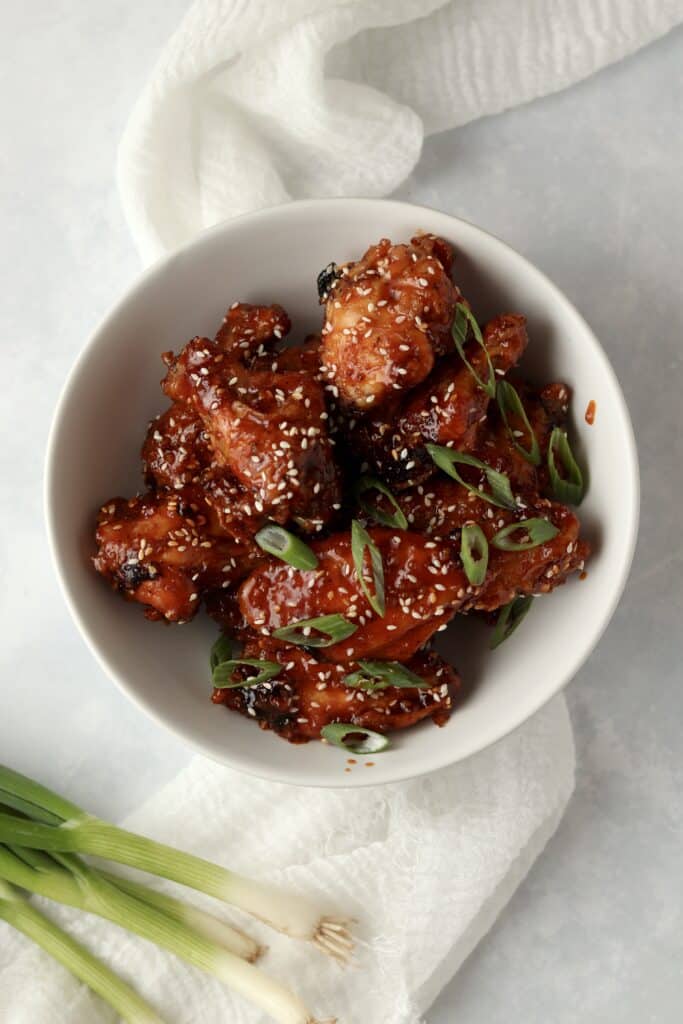 bowl of baked Korean wings with sesame seeds and green onions