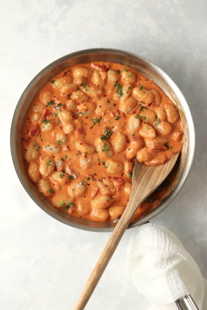 creamy gnocchi in skillet with wooden spoon