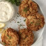 crab cakes on a plate with lemon and parsley