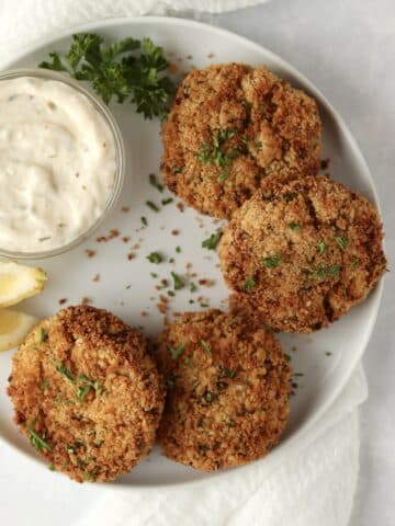 crab cakes on a plate with lemon and parsley