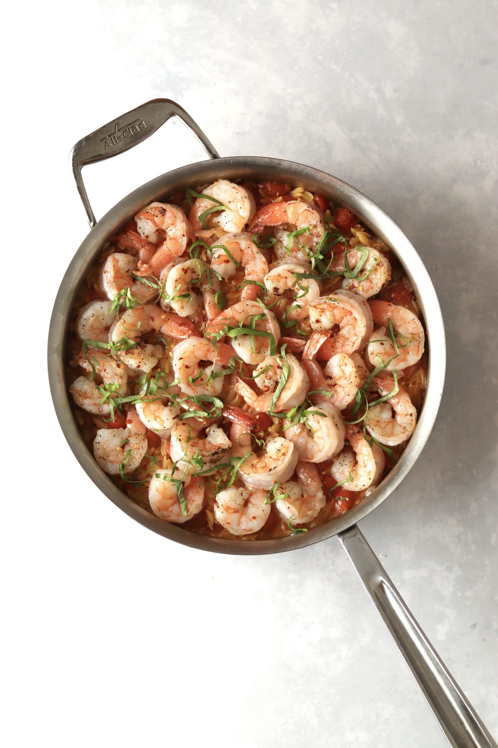 cooked shrimp on top of orzo with basil.