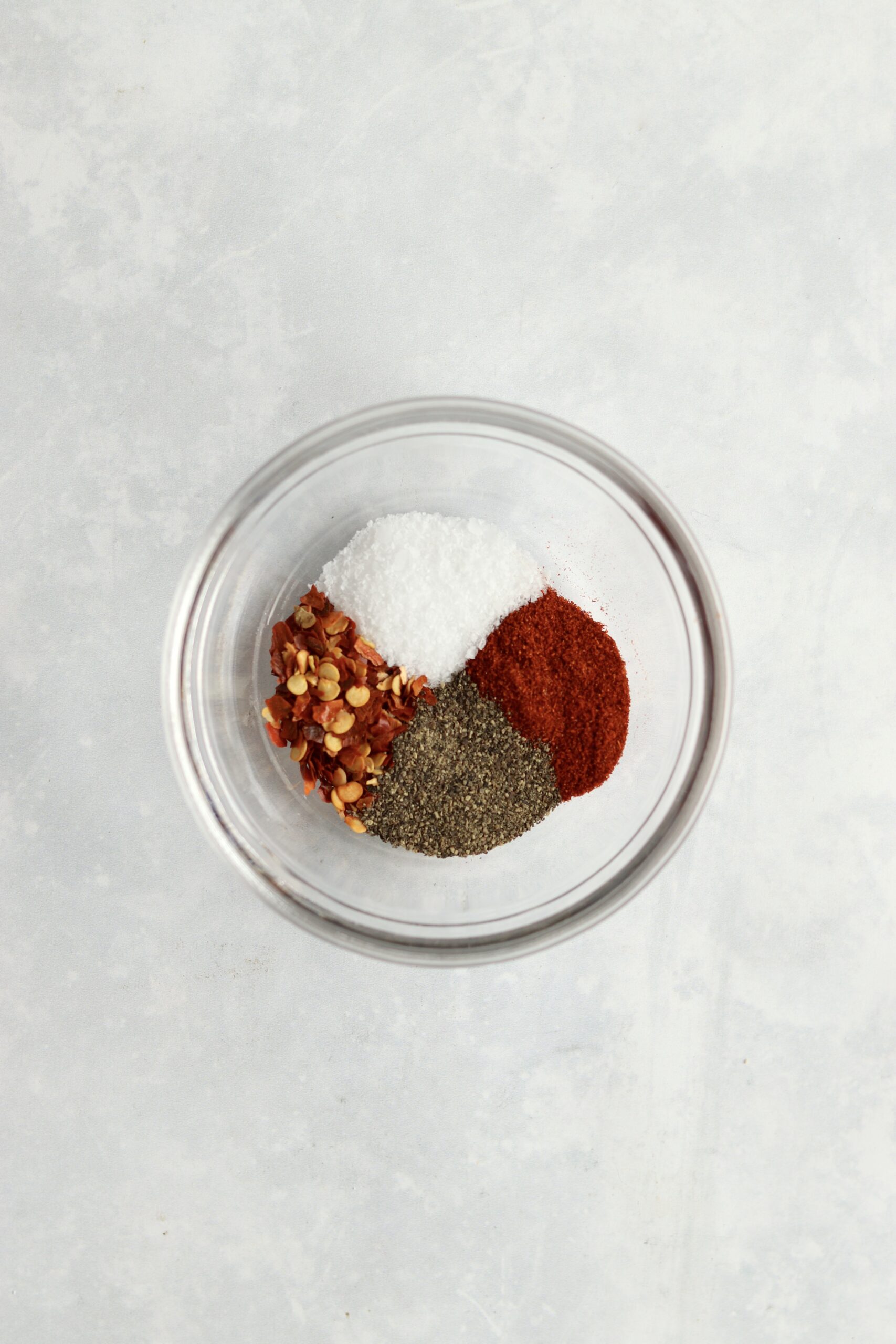 salt, pepper, paprika, and red pepper flakes in a bowl
