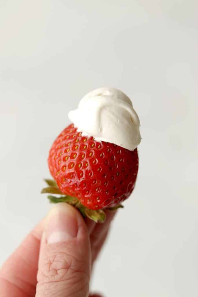 hand holding up a strawberry with dip