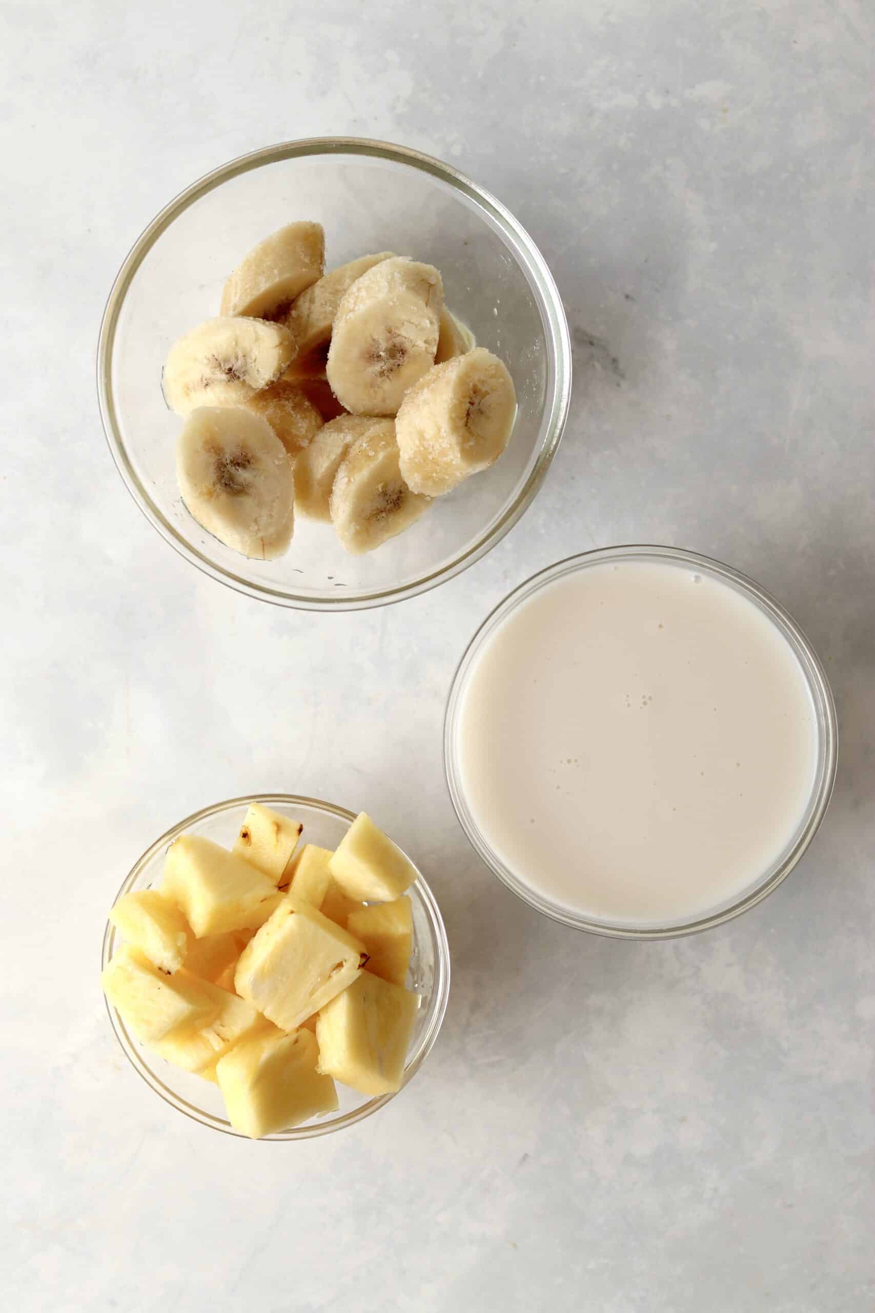 frozen banana, pineapple chunks, and almond milk in bowls