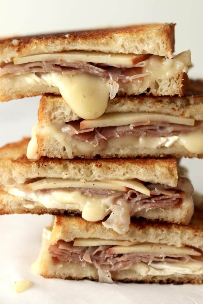 close up of melted brie grilled cheese sandwiches with prosciutto and apple