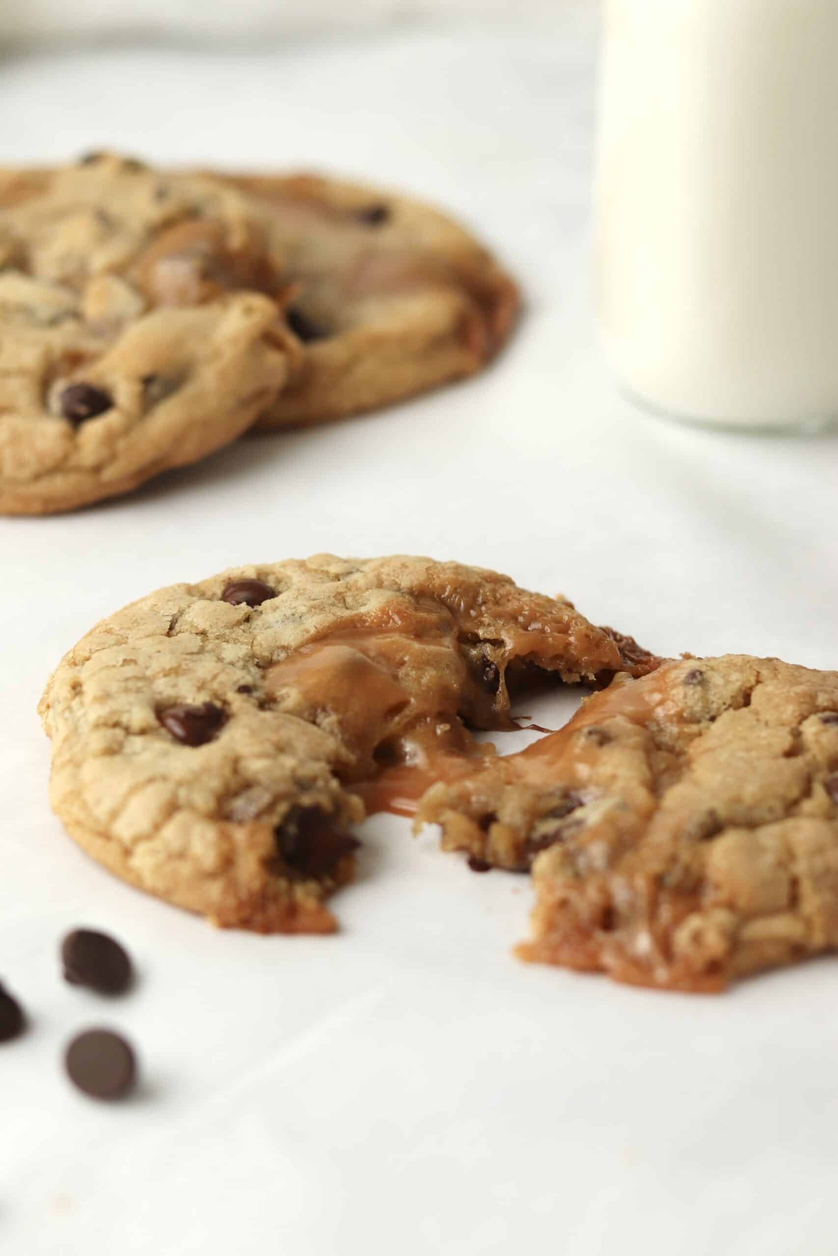 gooey caramel melted chocolate chip cookies with a glass of milk