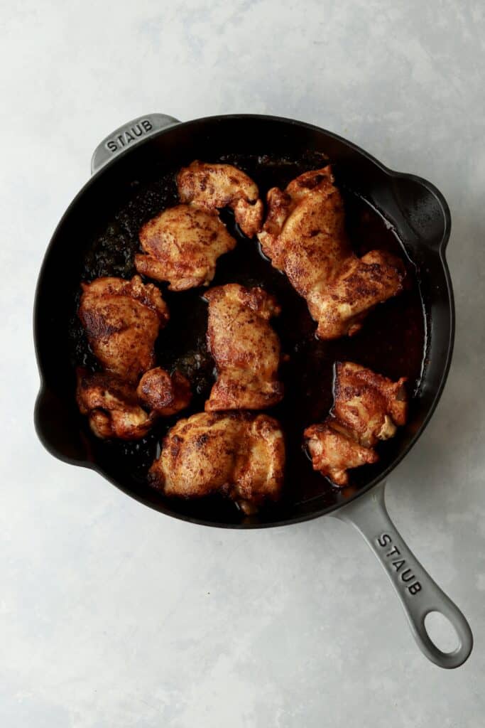 browned chicken thighs in cast iron skillet