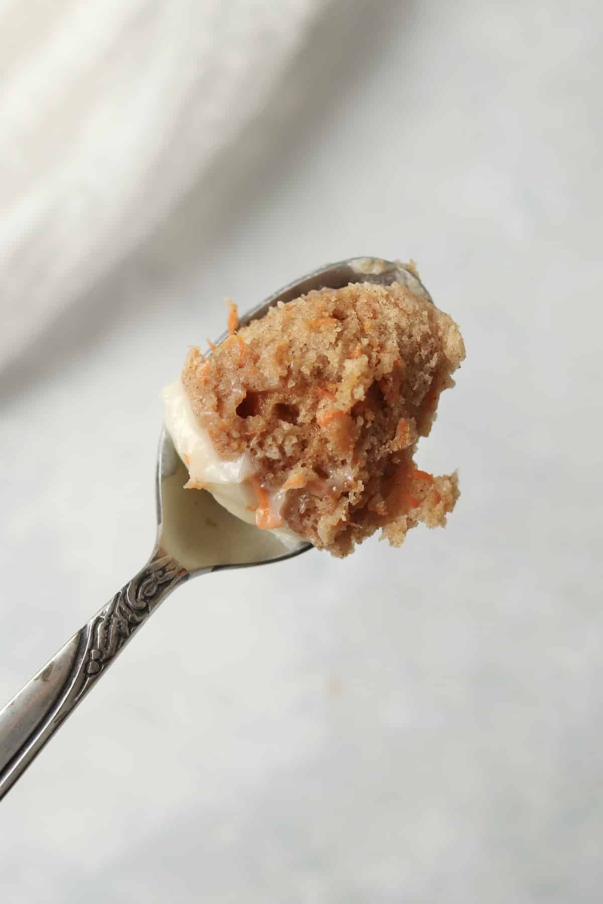 spoon holding bite of carrot cake that shows the grated carrots