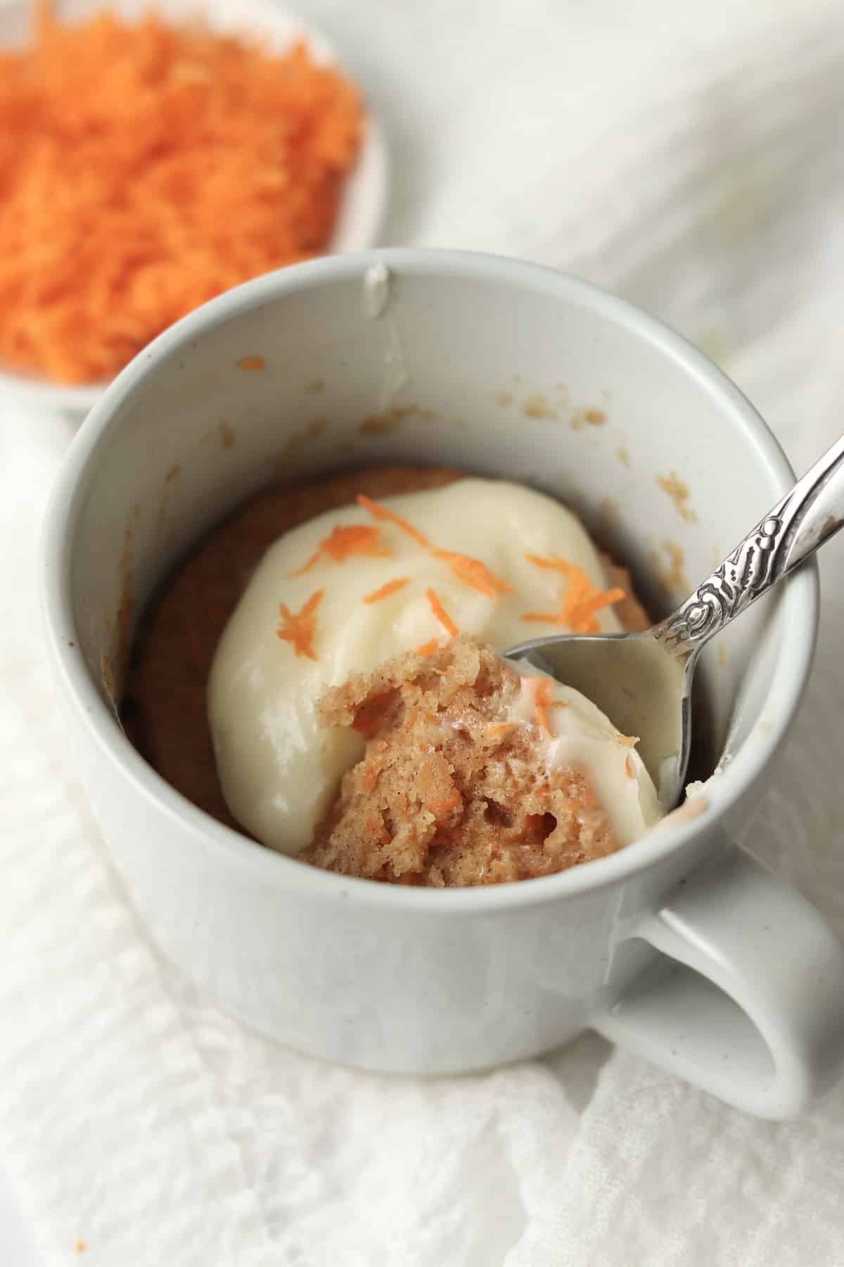 carrot mug cake with grated carrots in the background