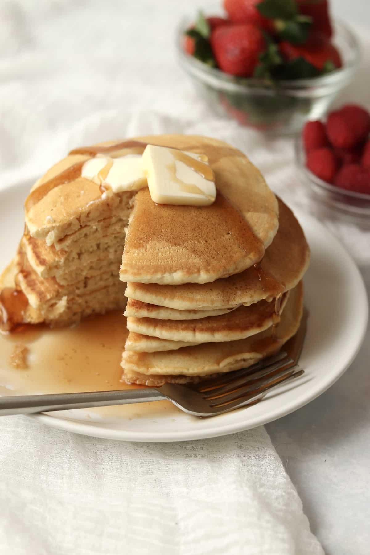 stack of homemade pancakes without milk served with berries and maple syrup