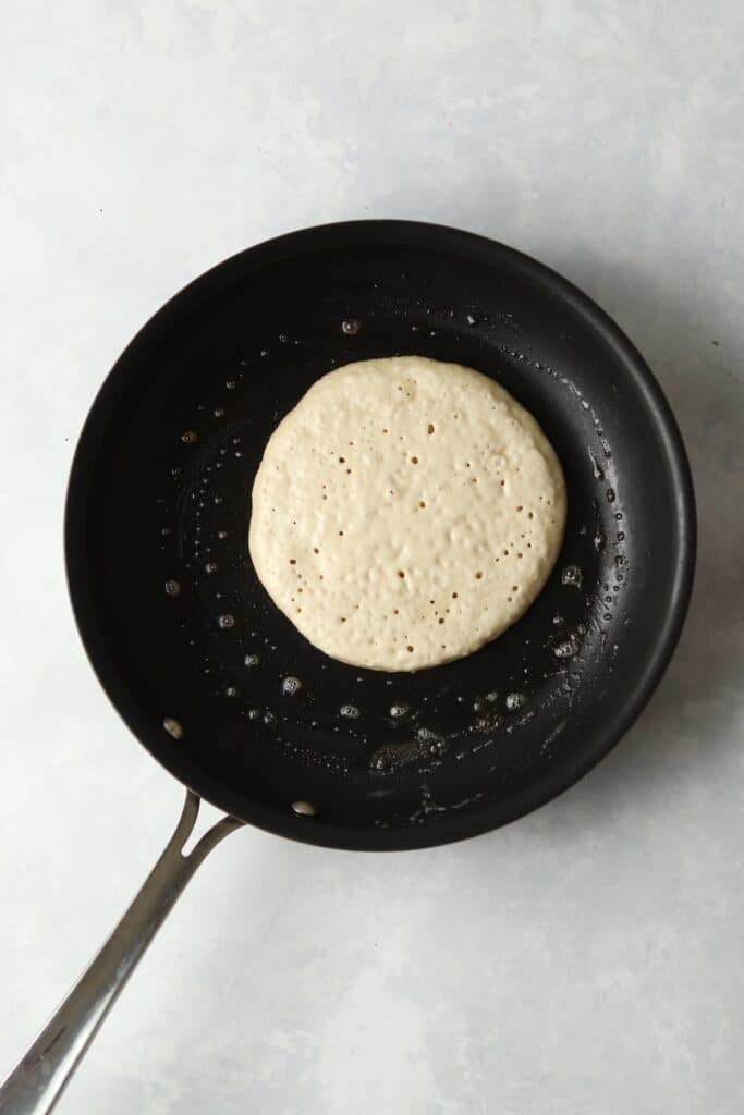 pancake in pan with bubbles on top before flipping