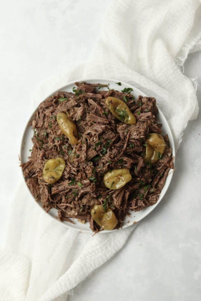 shredded beef on a plate with pepperoncini peppers