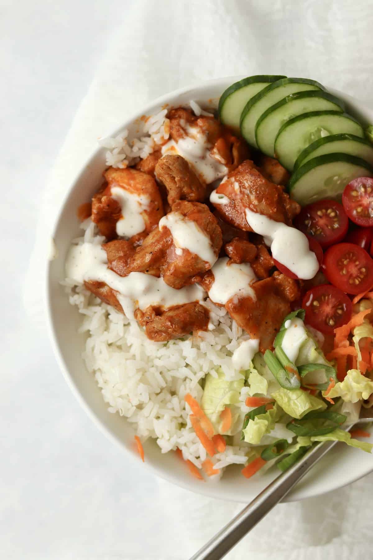 buffalo chicken rice bowl with cucumber and lettuce
