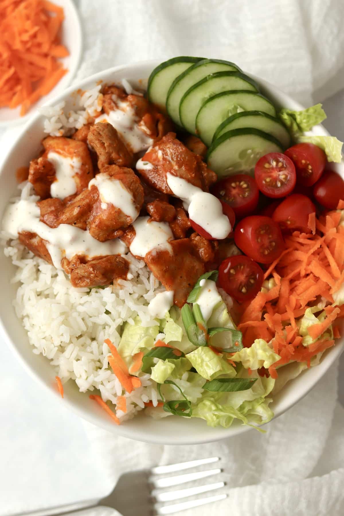 buffalo chicken rice bowl with cucumber, carrots, and ranch